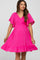 woman wearing a bright pink maternity dress with flutter sleeves and a tiered ruffle hem, showcasing her baby bump