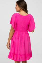 woman wearing a bright pink short sleeve maternity dress with a smocked bodice and tiered skirt from the back