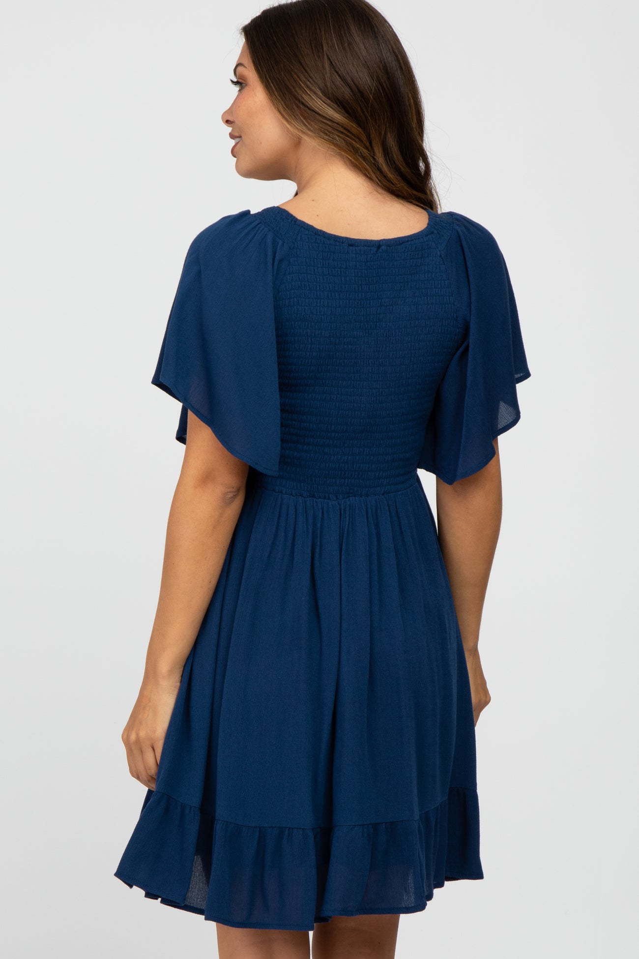 woman wearing a navy blue short sleeve maternity dress with a smocked bodice and flared skirt