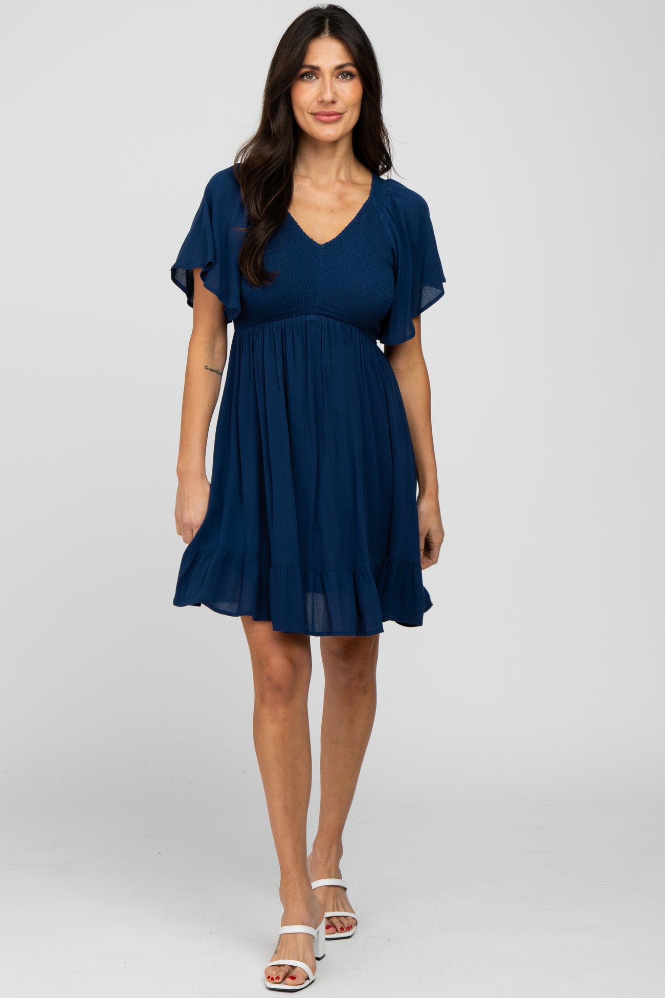 woman wearing a navy blue short sleeve maternity dress with a smocked bodice and ruffle hem