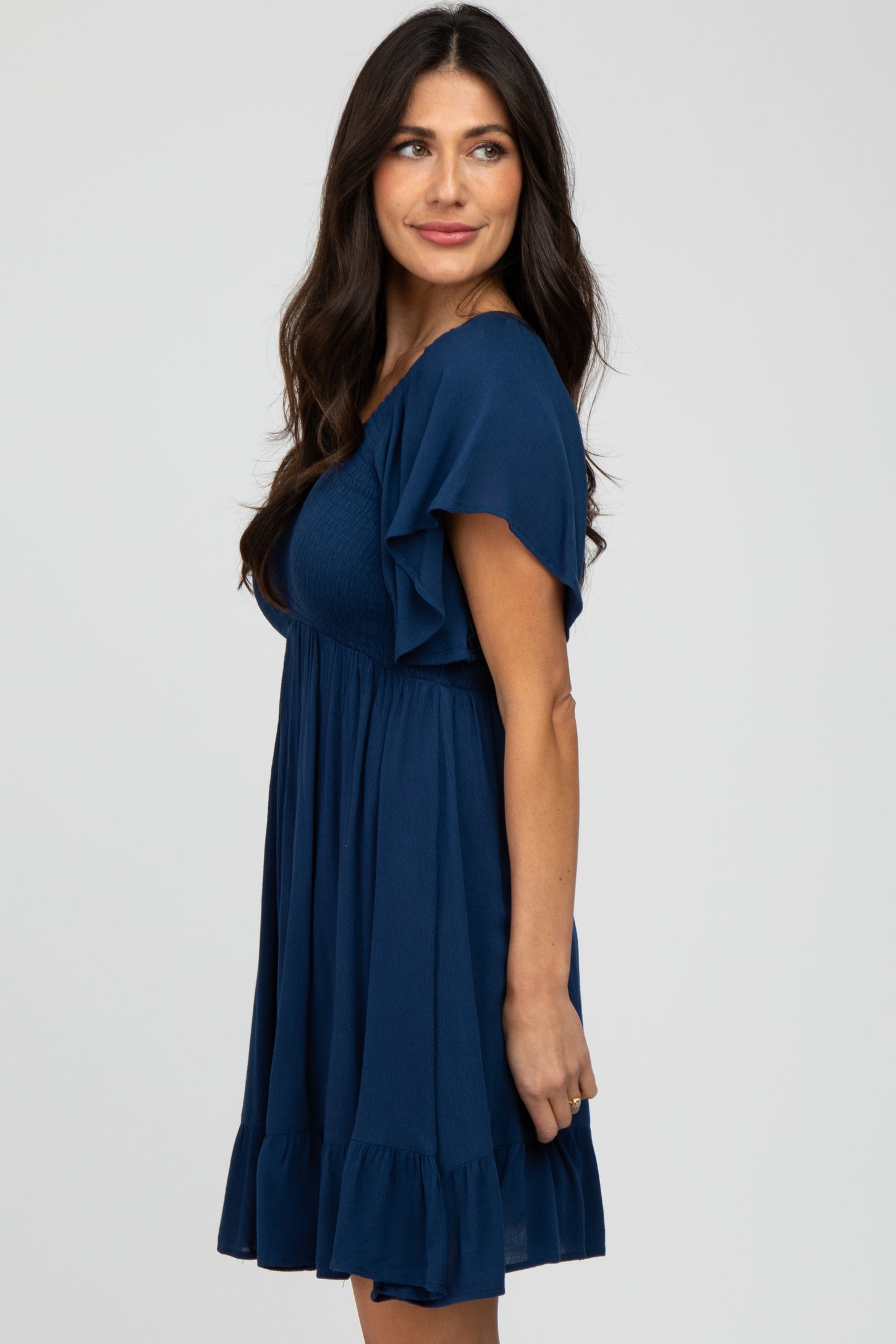 woman wearing a navy blue short sleeve dress with ruffle details and a fitted bodice