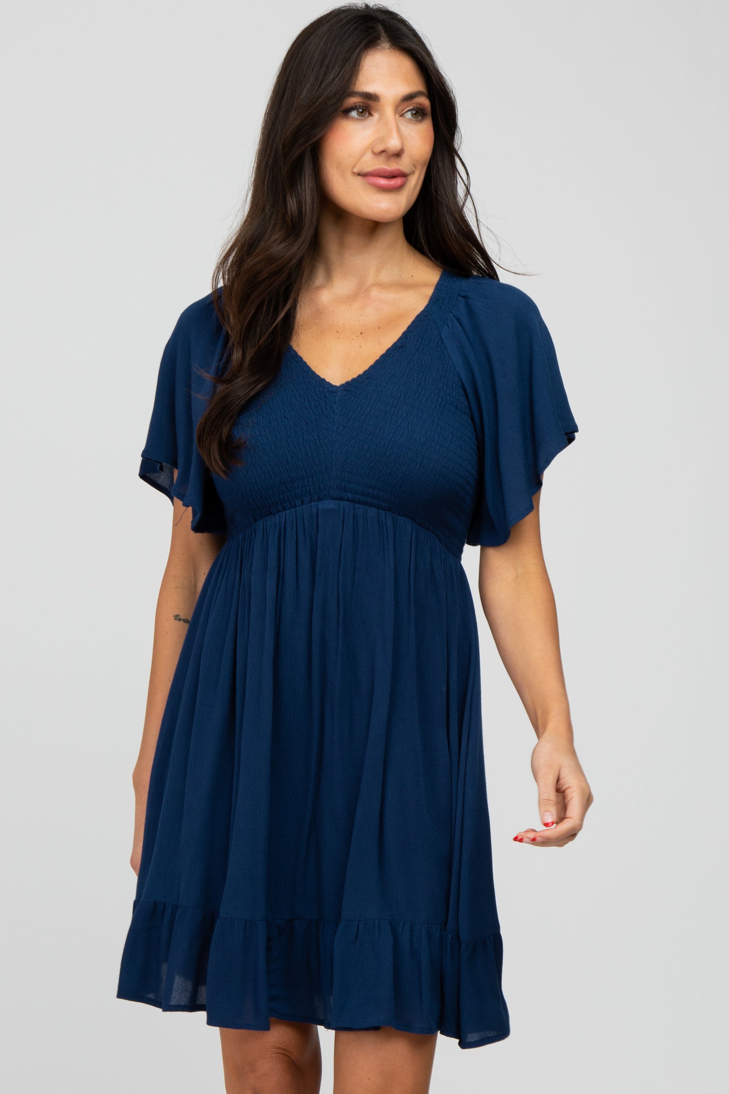 woman wearing a navy blue short sleeve maternity dress with a smocked bodice and ruffled hem