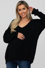 woman wearing a black oversized maternity sweater with a v-neck and holding her baby bump