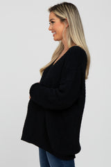 Blonde woman smiling in profile wearing an oversized black fuzzy knit sweater and blue jeans