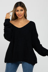 woman wearing a loose-fitting black off-the-shoulder sweater with long sleeves and a relaxed silhouette