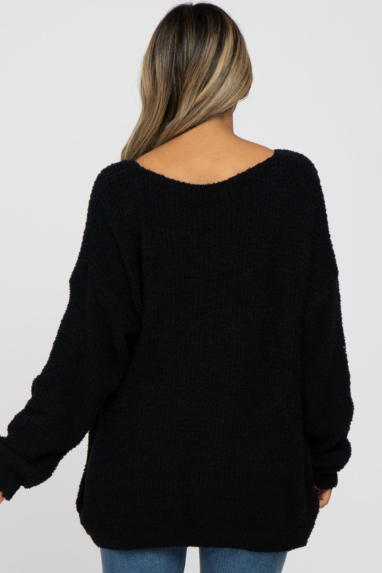 back view of a woman wearing a black fuzzy knit oversized sweater with a scoop neckline