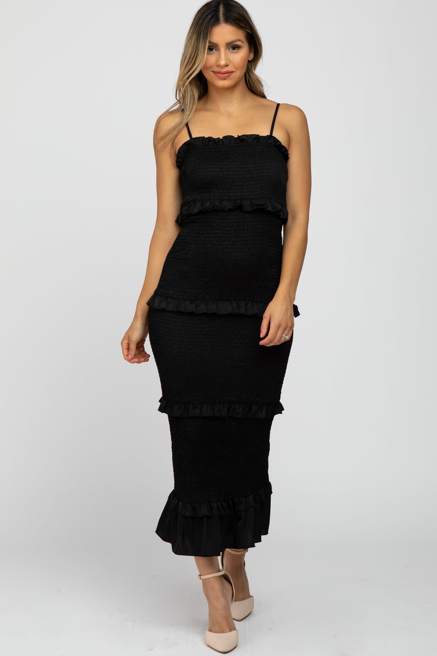woman wearing a black smocked tiered maternity midi dress with ruffle trim and spaghetti straps