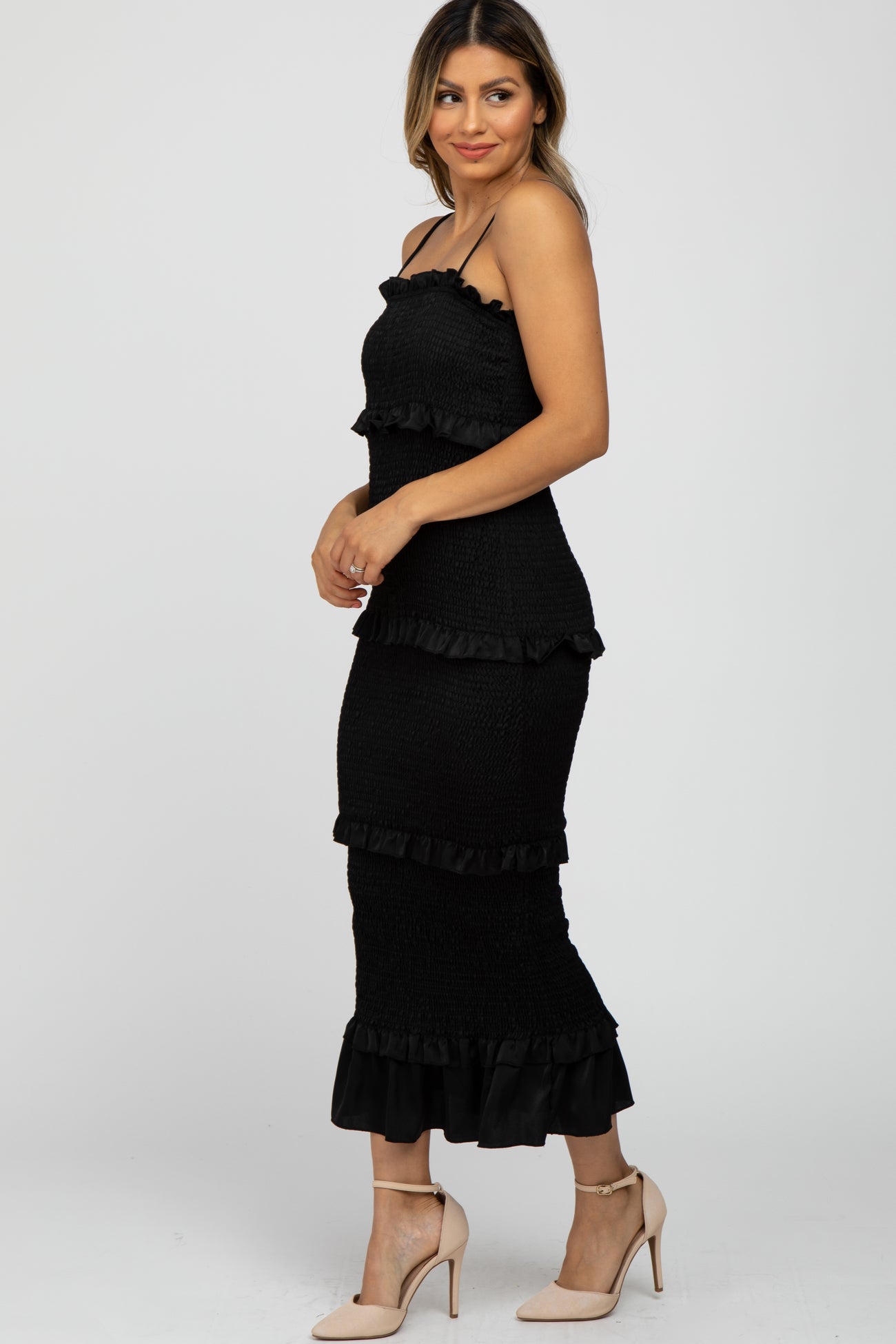 woman wearing a black tiered strapless dress with ruffle details and paired with nude high heels