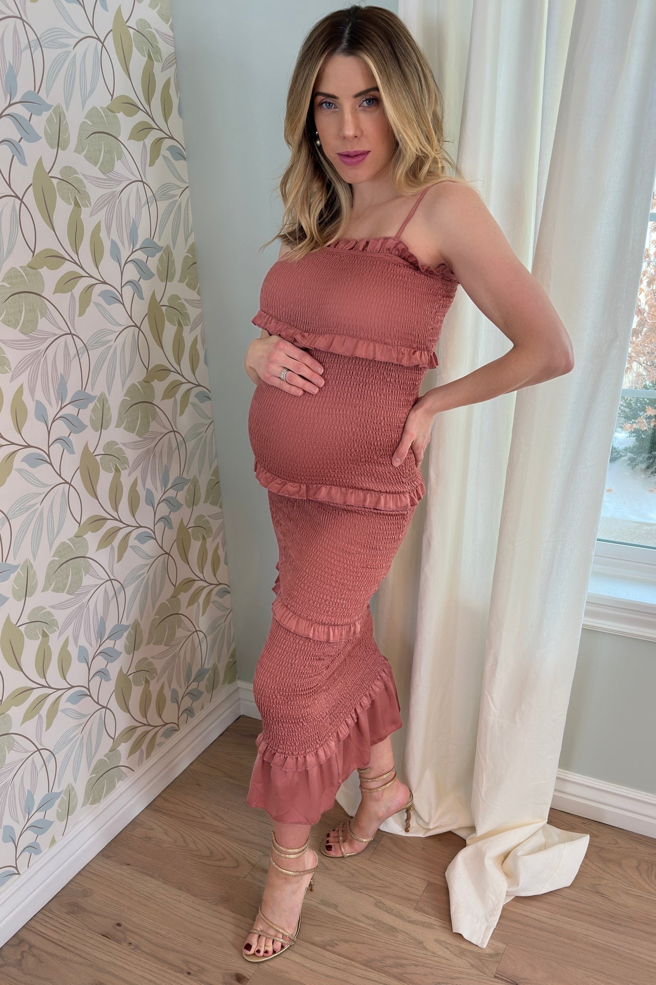 woman wearing a rust-colored maternity dress with ruffle details and a visible baby bump