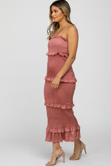 Woman wearing a mauve smocked tiered midi dress and beige high heels against a white background