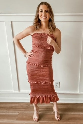 woman wearing a rust colored smocked midi dress with ruffle tiers and spaghetti straps