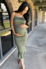 woman wearing a light olive green maternity dress with ruffle details and a visible baby bump