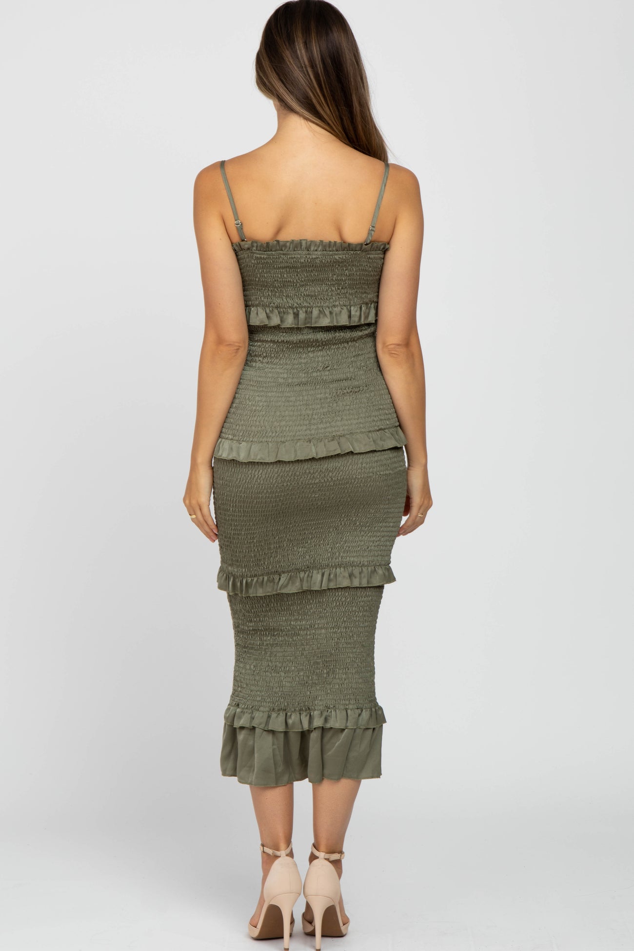 woman wearing a green maternity dress with ruffle details and a fitted silhouette, showing off a baby bump from behind