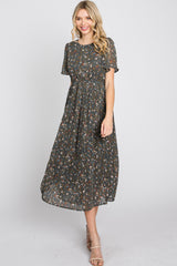 woman wearing a dark floral midi dress with short sleeves and a pleated skirt, smiling and standing in a relaxed pose