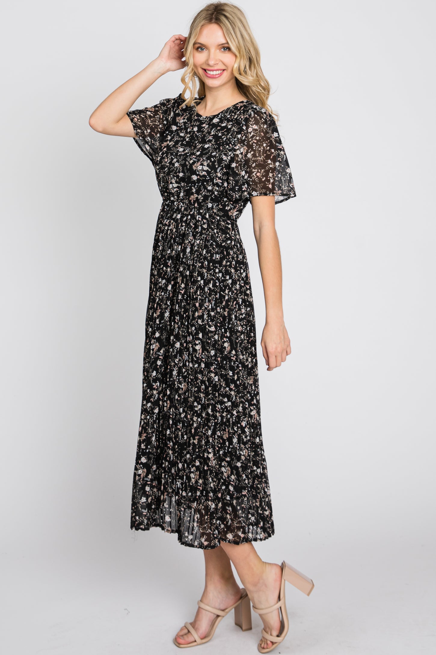 woman wearing a black floral midi dress with short flutter sleeves and a cinched waist