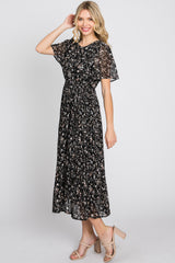 woman wearing a black floral midi dress with short flutter sleeves and a cinched waist