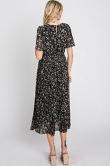 woman wearing a black floral midi dress with short sleeves and a pleated skirt, viewed from the back