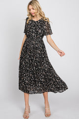 woman wearing a black floral midi dress with short sleeves and a smocked bodice, styled with strappy heels