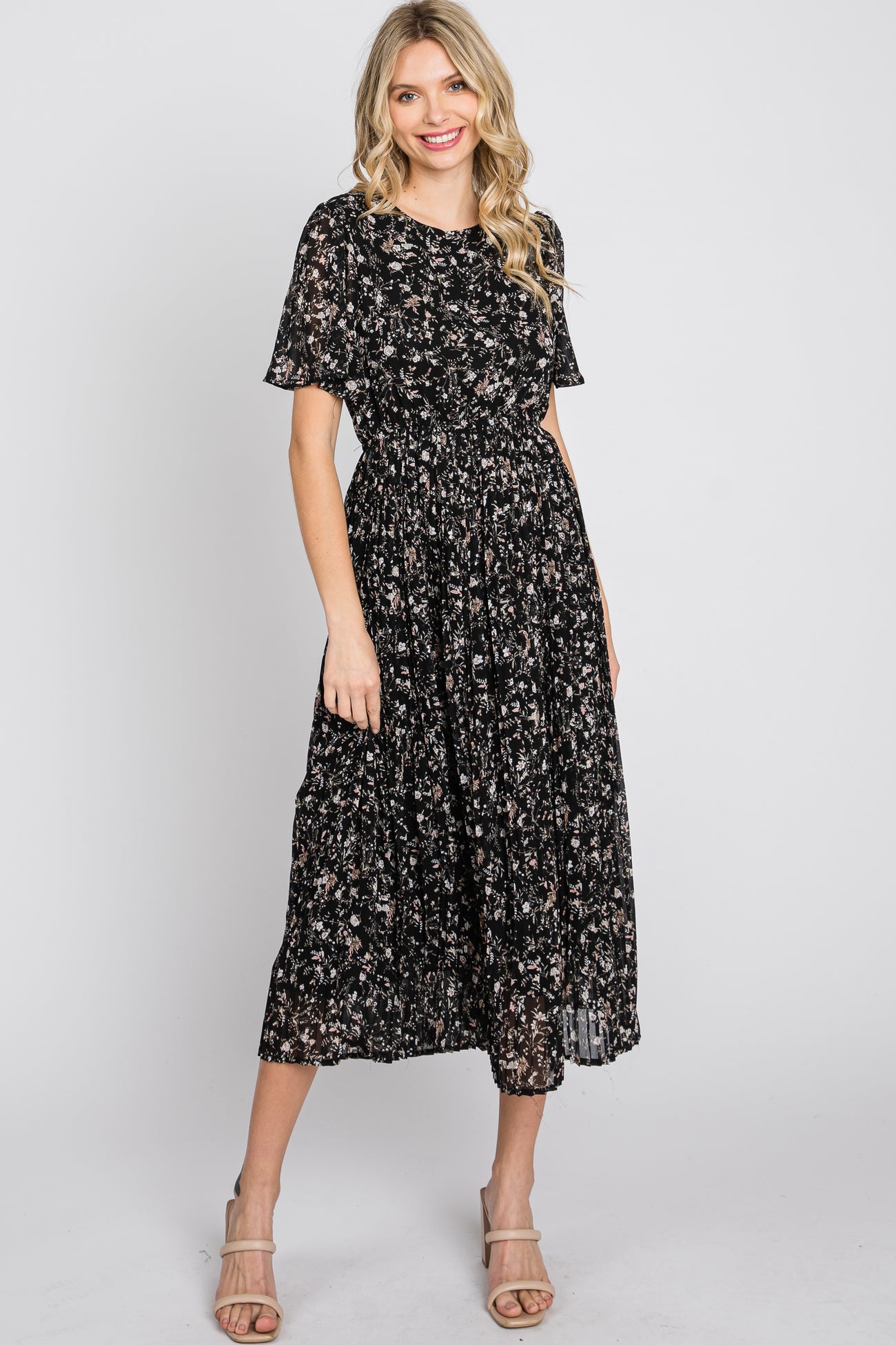 woman wearing a black floral print midi dress with short sleeves and a cinched waist