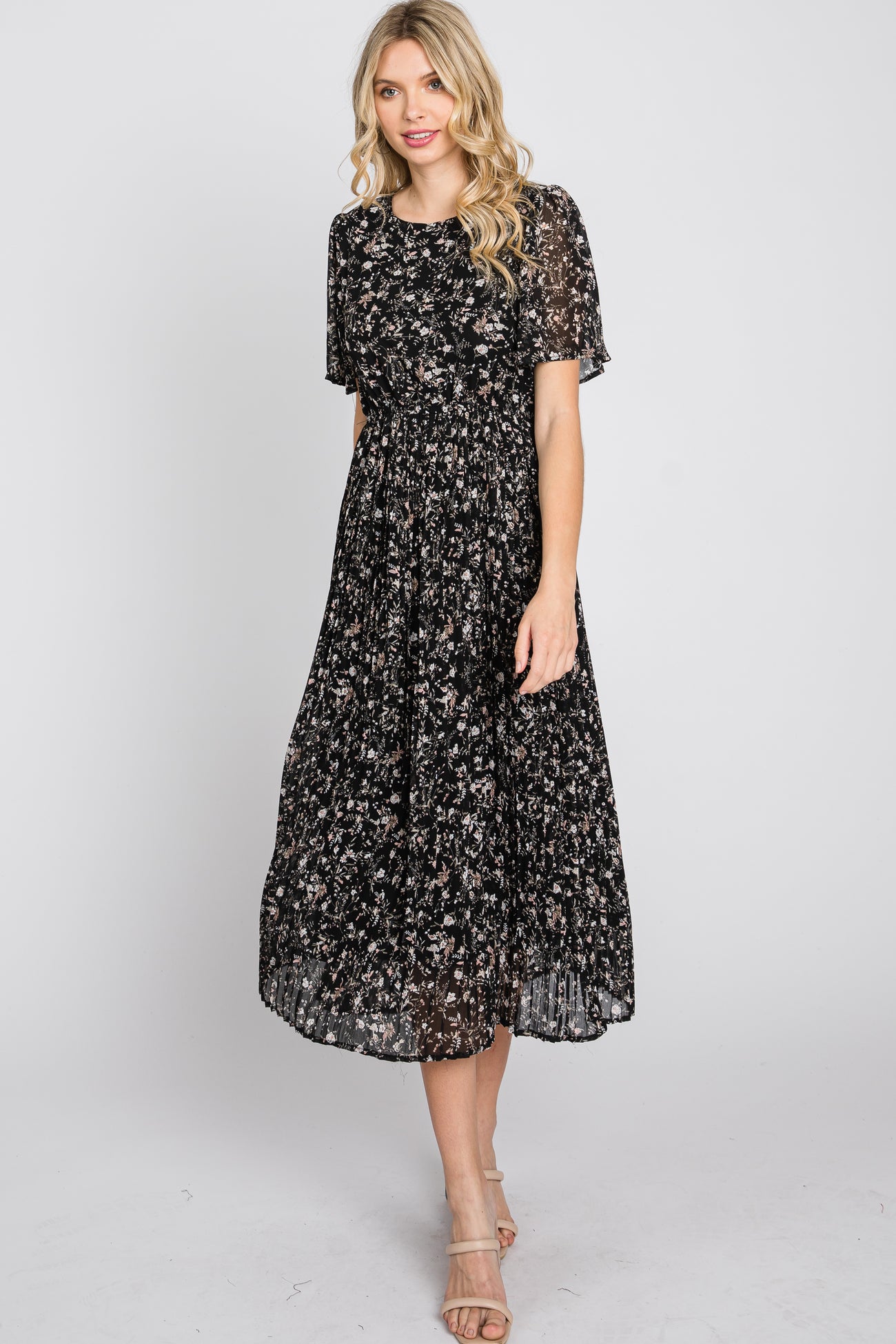 woman wearing a black floral midi dress with short sleeves and a pleated skirt
