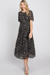 woman wearing a black floral midi dress with short sleeves and a pleated skirt