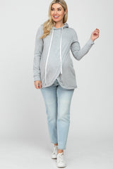 woman wearing a gray maternity hoodie with a drawstring and a baby bump visible, paired with light wash jeans