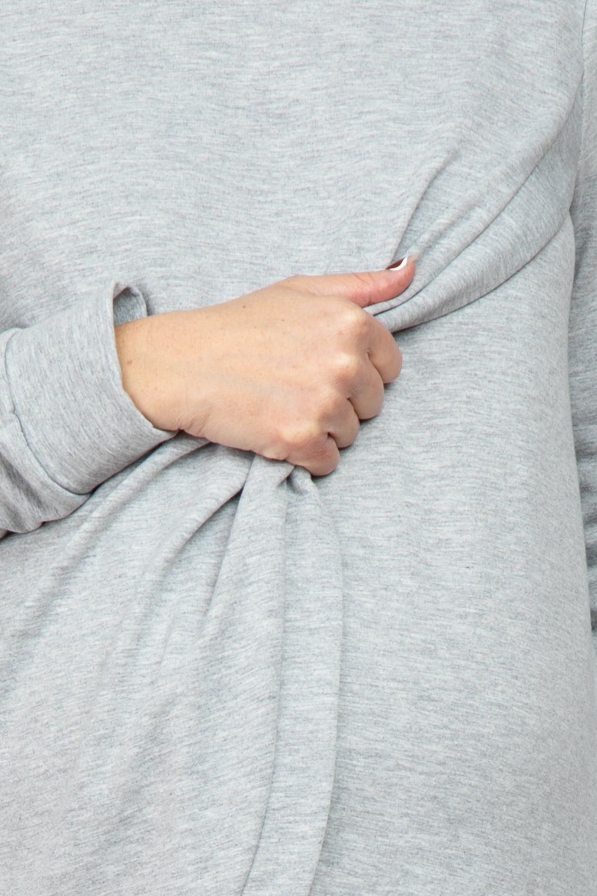 woman wearing a light gray maternity top with a knotted detail at the hip and a visible baby bump