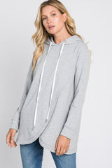 woman wearing a gray hooded sweatshirt with a curved hem and white drawstrings, paired with blue jeans