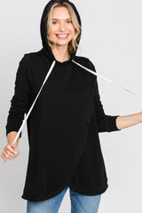 smiling woman wearing a black nursing hoodie with white drawstrings and tulip hem over blue jeans