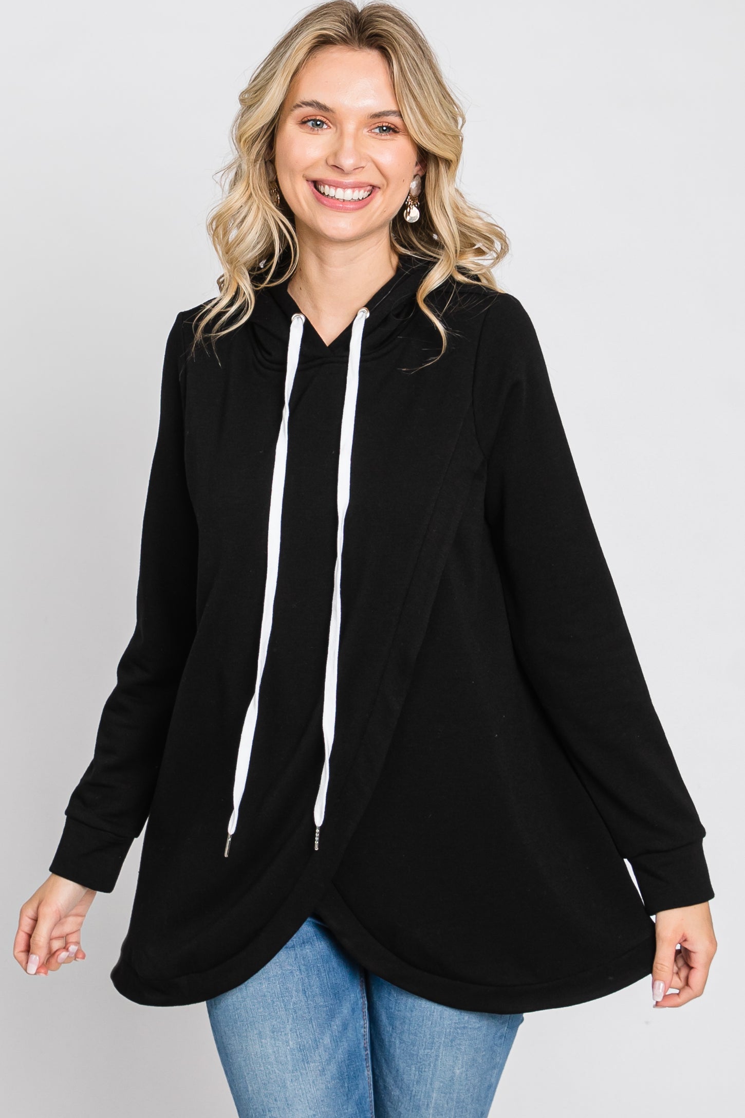 woman wearing a black oversized hoodie with white drawstrings and a flowy hem, paired with blue jeans
