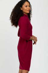 woman wearing a burgundy three-quarter sleeve fitted dress with a mock neck