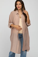 woman wearing a light brown maternity shirt dress with rolled sleeves and a visible baby bump