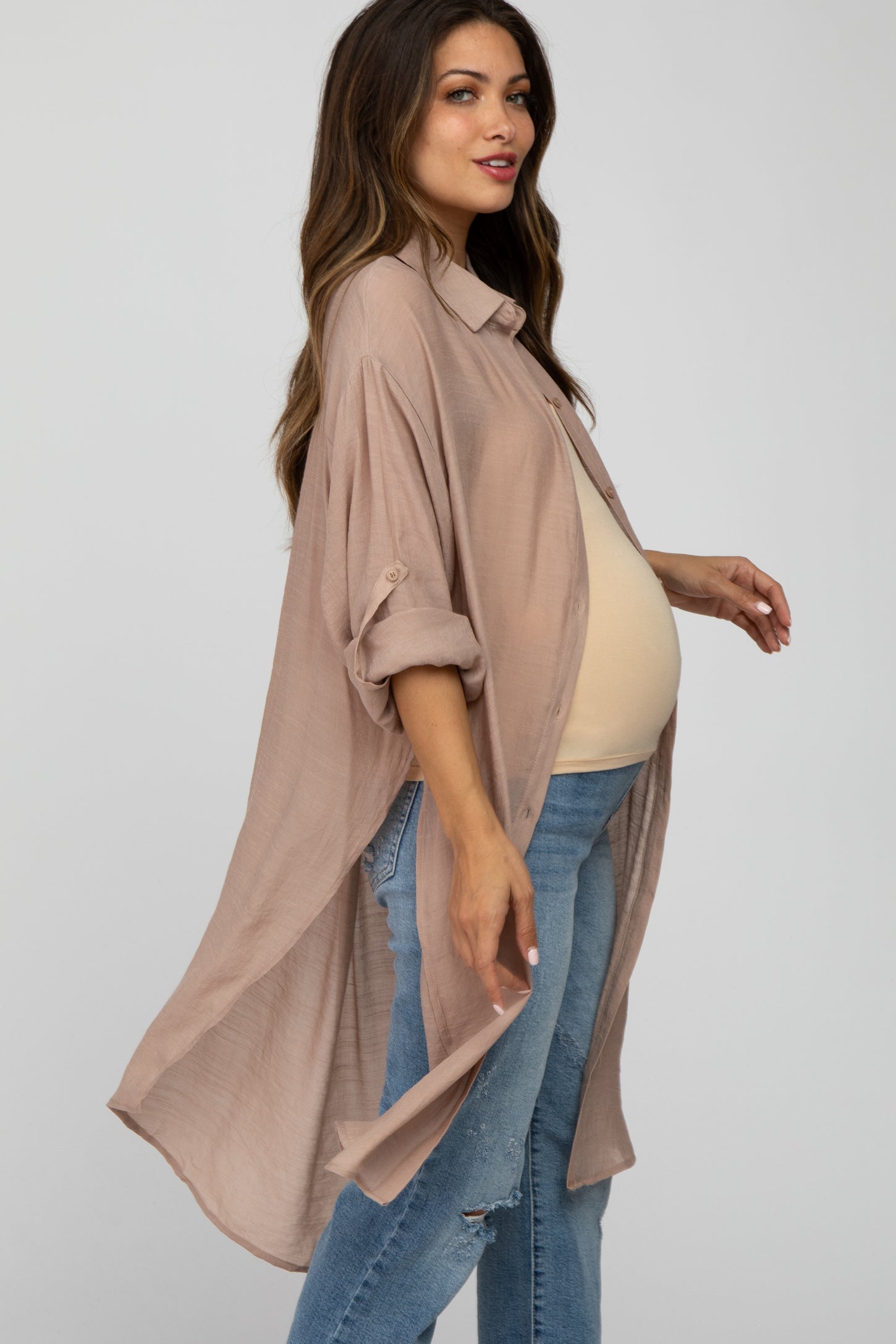 woman wearing a light taupe maternity tunic shirt with rolled sleeves and a visible baby bump