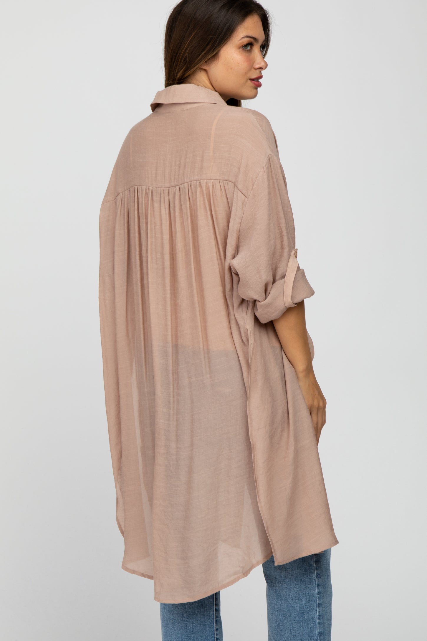 woman wearing a light pink oversized maternity shirt with a relaxed fit and rolled sleeves