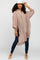 woman wearing a light pink oversized button-up shirt with rolled sleeves and dark skinny jeans, posing with a cap