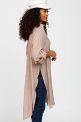 woman wearing a light pink long sleeve tunic with a high-low hem and rolled sleeves, styled with dark jeans and a white cap
