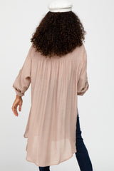 woman wearing a light pink long sleeve tunic with a curved hem and gathered back detail, seen from the back