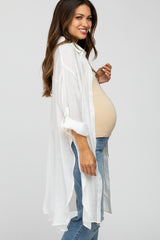 woman wearing a white long sleeve maternity cardigan over a beige top and showing off her baby bump