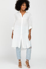 woman wearing a white long sleeve button-up tunic top with rolled sleeves and light blue distressed jeans