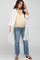 woman wearing a long white button-up shirt over a beige maternity tank top and distressed jeans, showing a baby bump