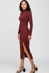 woman wearing a maroon long sleeve ribbed midi dress with a side slit and styled with black strappy heels