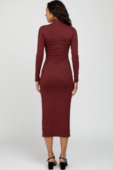 woman wearing a burgundy long sleeve midi dress with a high neck and form-fitting silhouette, viewed from the back