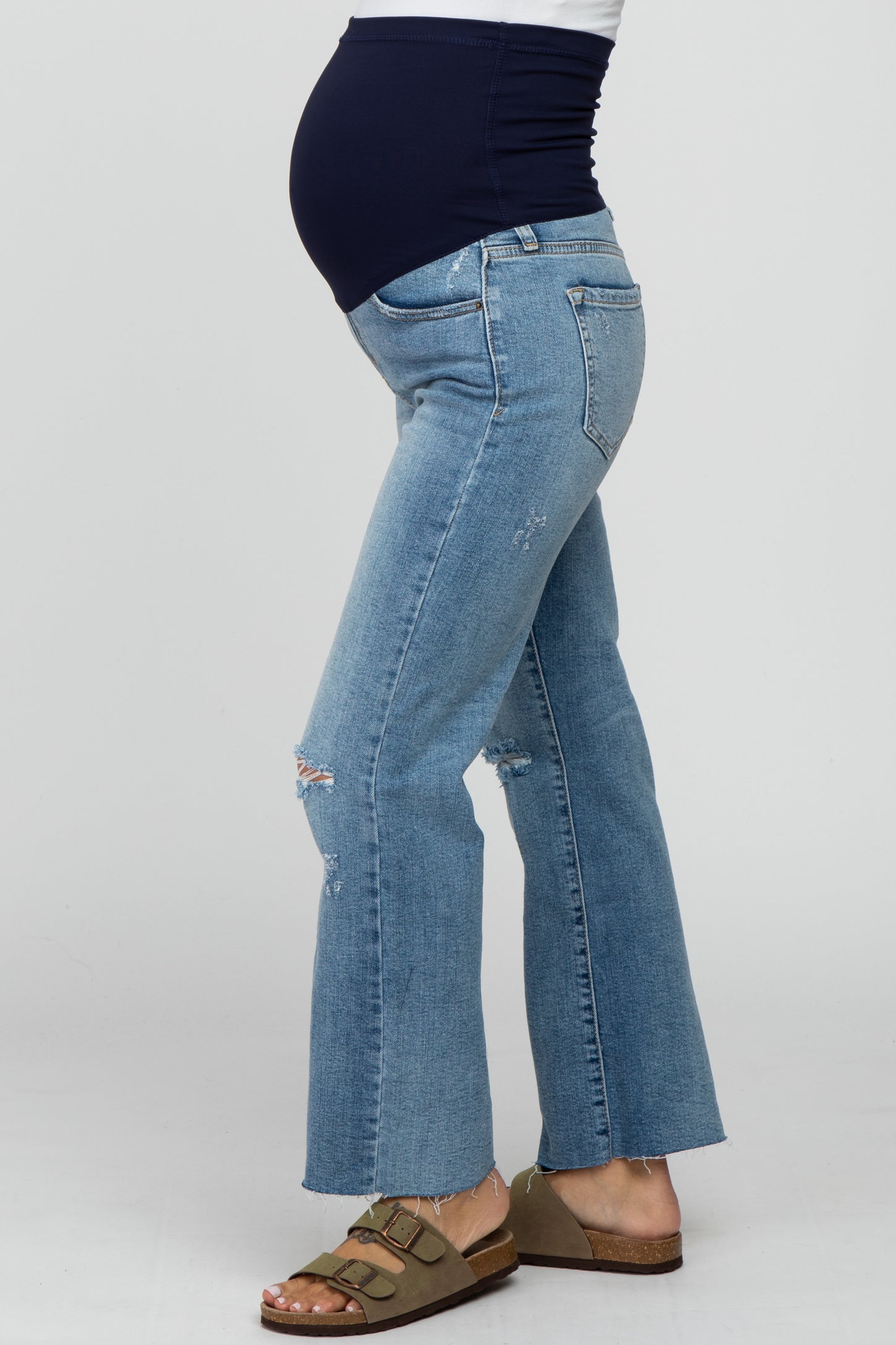 pregnant woman wearing distressed light wash maternity flare jeans with a navy blue belly band