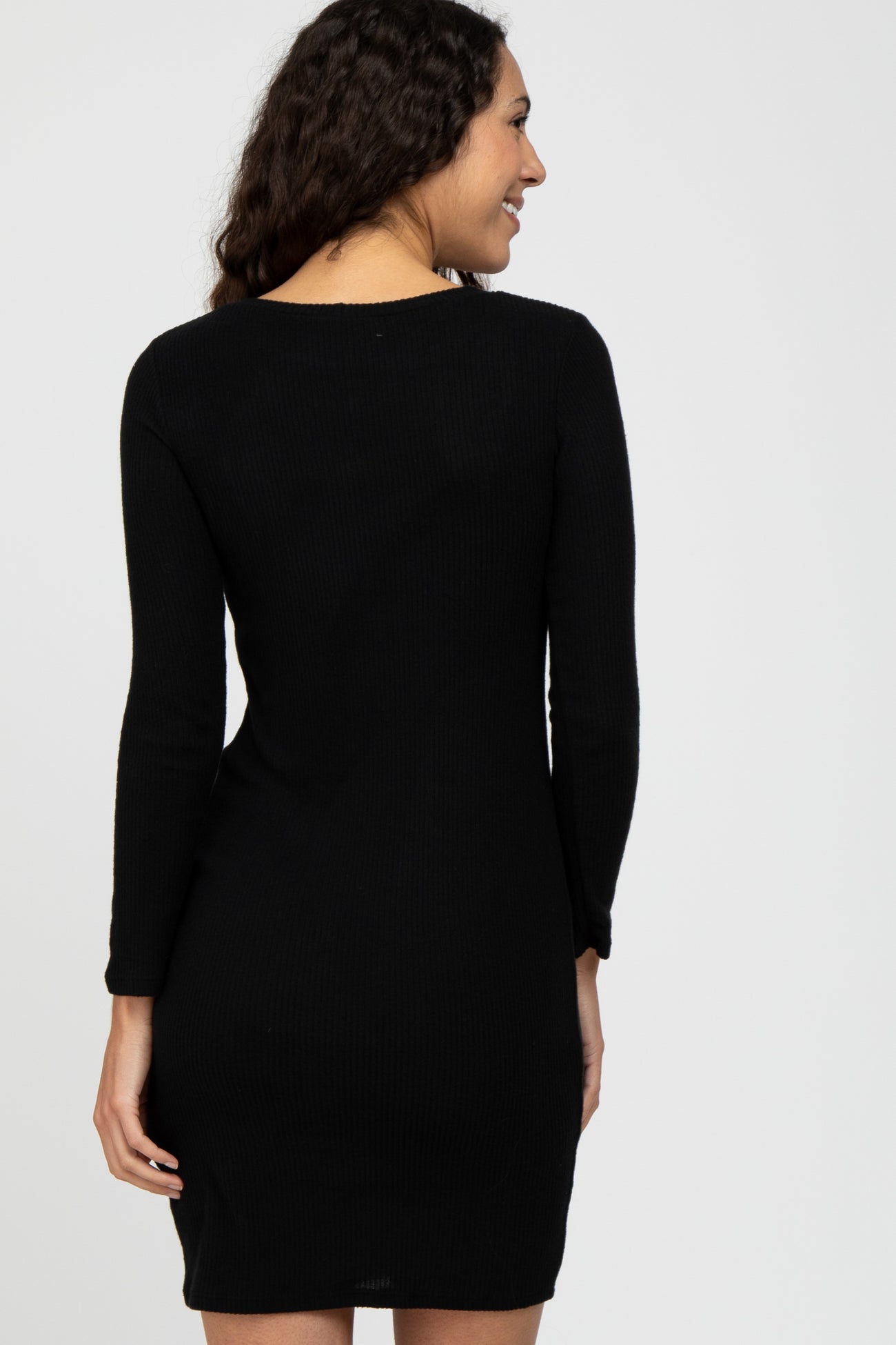 woman wearing a black ribbed long sleeve dress, shown from the back