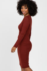woman wearing a rust long sleeve ribbed midi dress, smiling and posing sideways