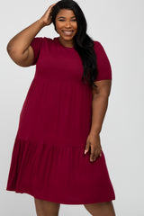 smiling woman in a short sleeve burgundy tiered ribbed knit dress against a white background