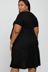 Woman wearing a short sleeve black tiered maternity dress against a white background