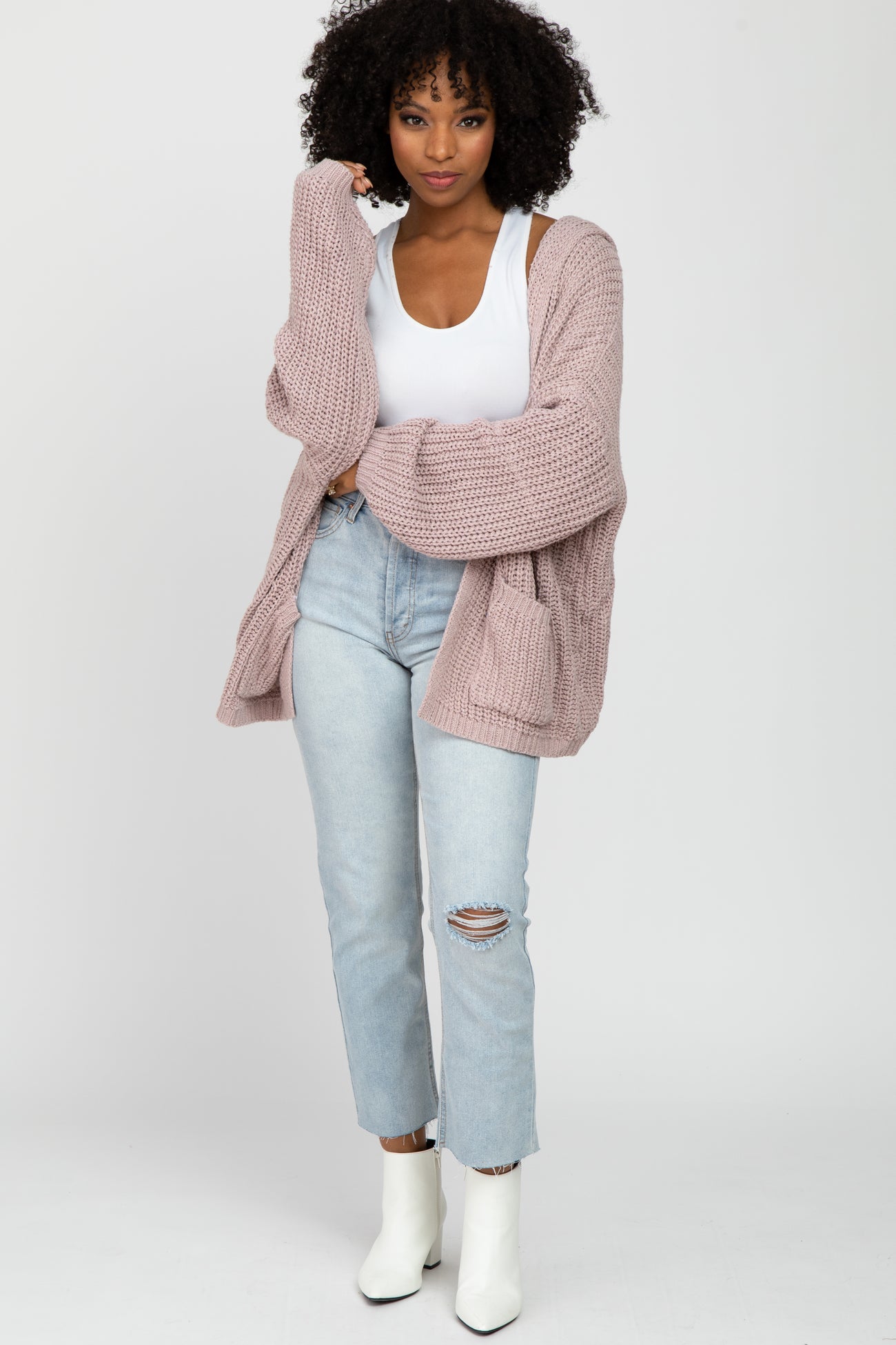 woman wearing oversized mauve knit cardigan with white tank top and light wash distressed jeans
