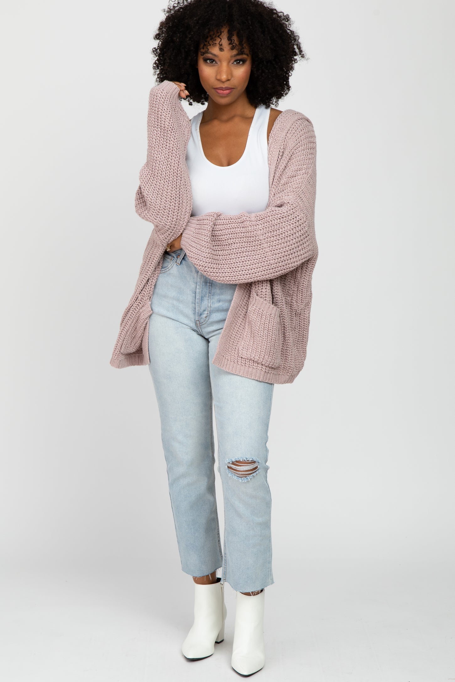 woman wearing oversized mauve knit cardigan with white tank top and light wash distressed jeans