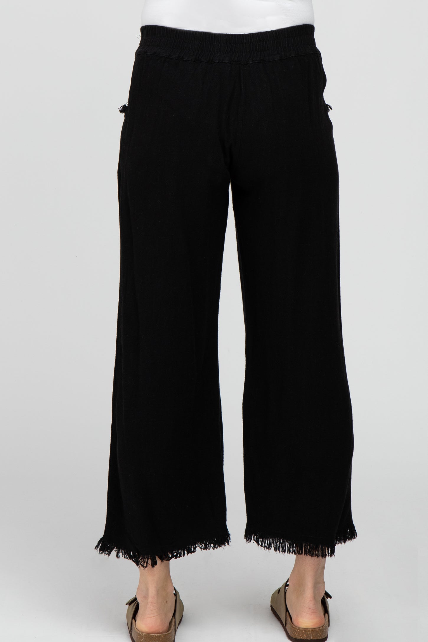 woman wearing black maternity palazzo pants with a fringed hem and an elastic waistband, viewed from the back